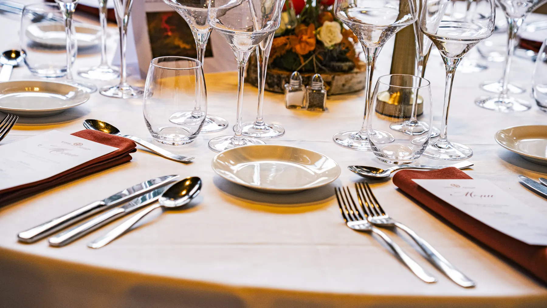 Détail d’un couvert dressé : argenterie, serviette bordeaux et menu