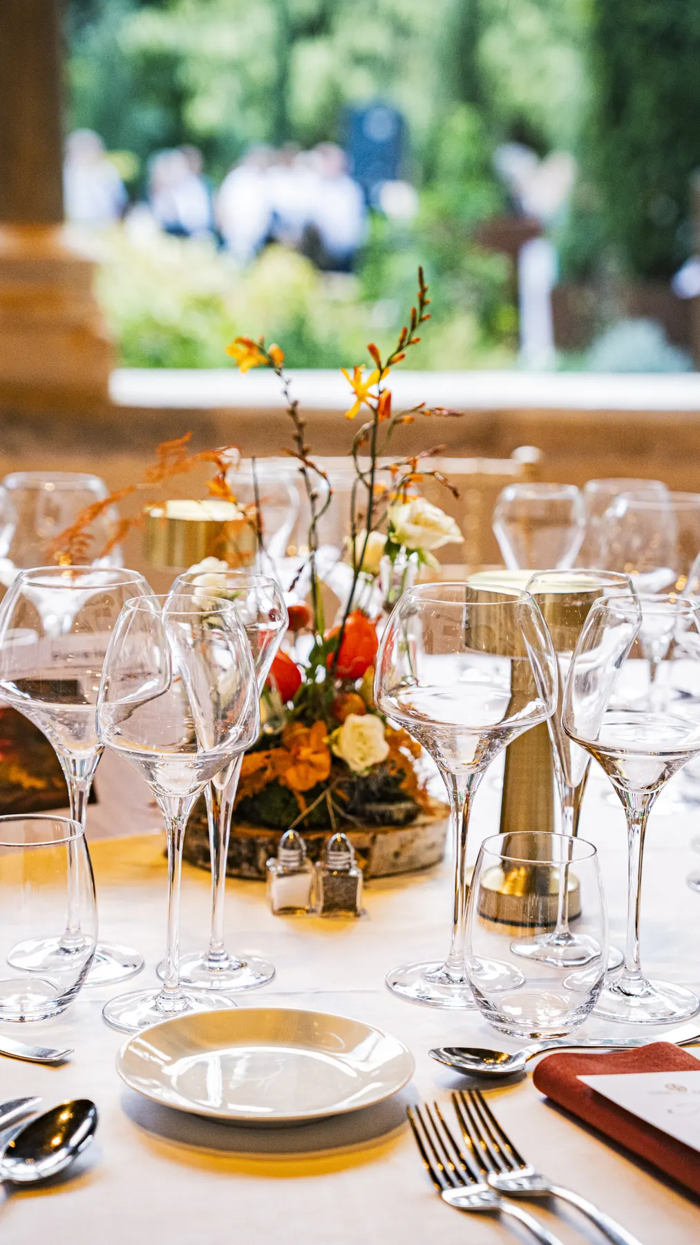Centre de table fleuri aux tons d’automne et verrerie sur nappe blanche