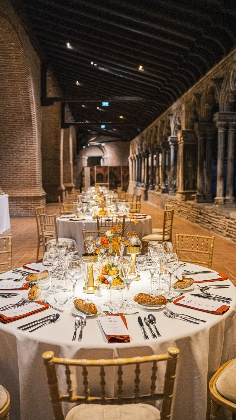 Tables rondes dressées et éclairées aux bougies dans la galerie du cloître des Augustins