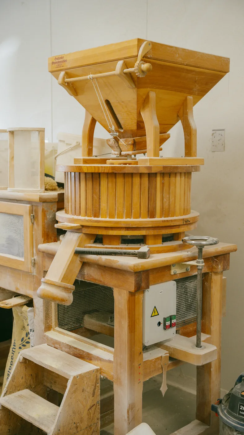 Moulin en bois à trémie installé dans l’atelier de la ferme